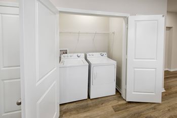 A white door is open to a laundry room with two washing machines.